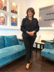 Woman in professional attire standing confidently in a modern office lounge, symbolizing leadership and executive presence.